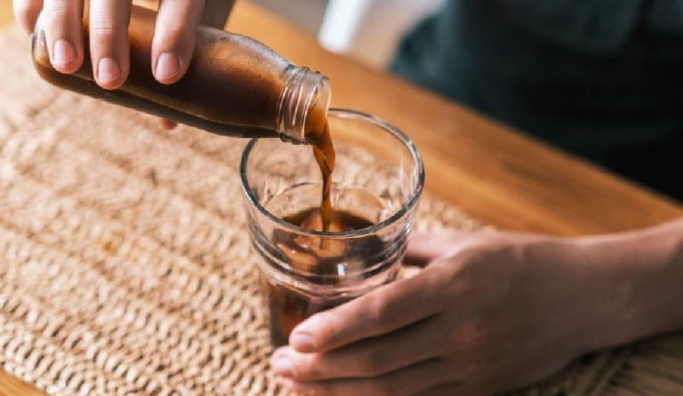 Pouring a glass of cold brew coffee from a bottle