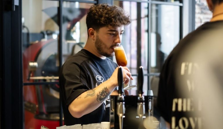 A barista sipping a drink dispensed from a cold brew coffee nitro tap.