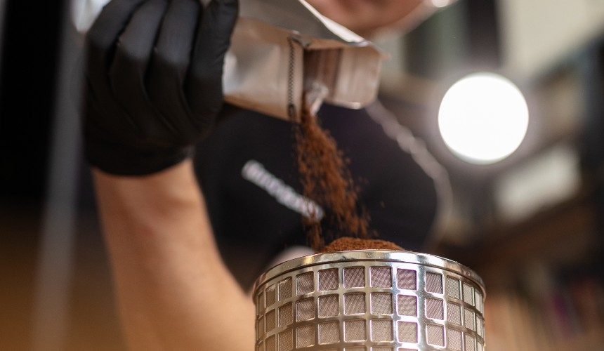 What is the amount of caffeine in cold brew? (and tips to control it) 2 A barista pouring coffee grounds into a filter basket.