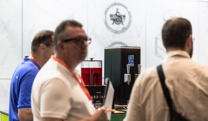 How a commercial drink machine boosts efficiency & menu variety 2 Attendees at a trade show walking past a Hardtank commercial drink machine.