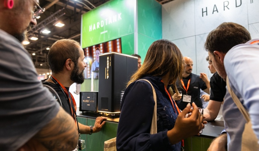 People at a trade show stood around nitro cold brew equipment.
