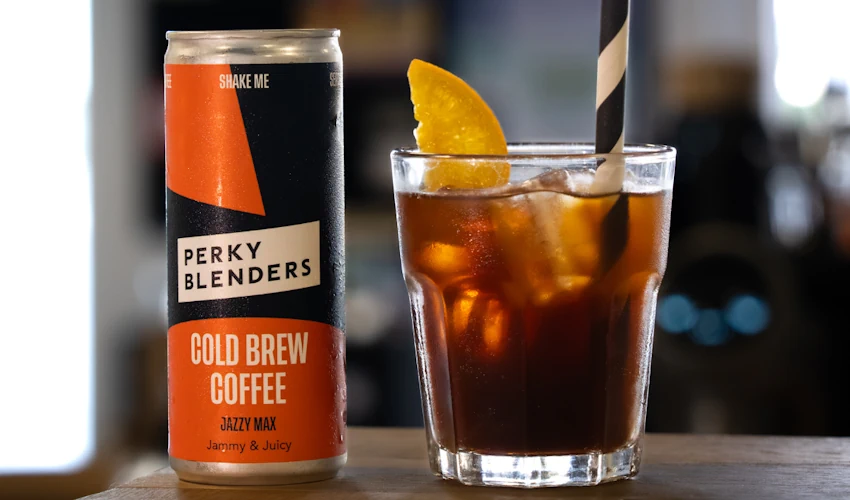 Canned Jazzy Max Perky Blenders cold brew coffee next to a glass of cold brew.