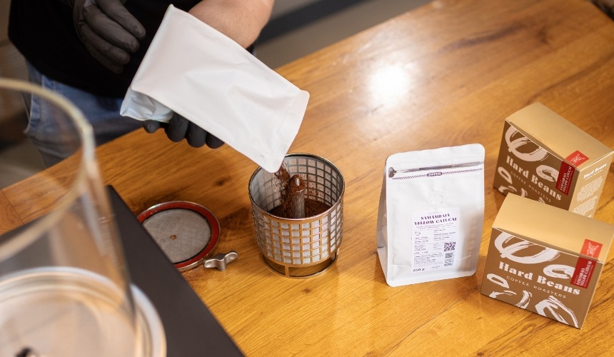A barista pouring coffee grounds into the Baby Hardtank's filter basket.